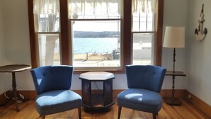 Una habitación con dos sillones azules mirando hacia una ventana con vista al agua.