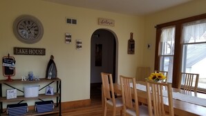 Un comedor con sillas de madera y una mesa, un reloj en la pared y varios adornos.