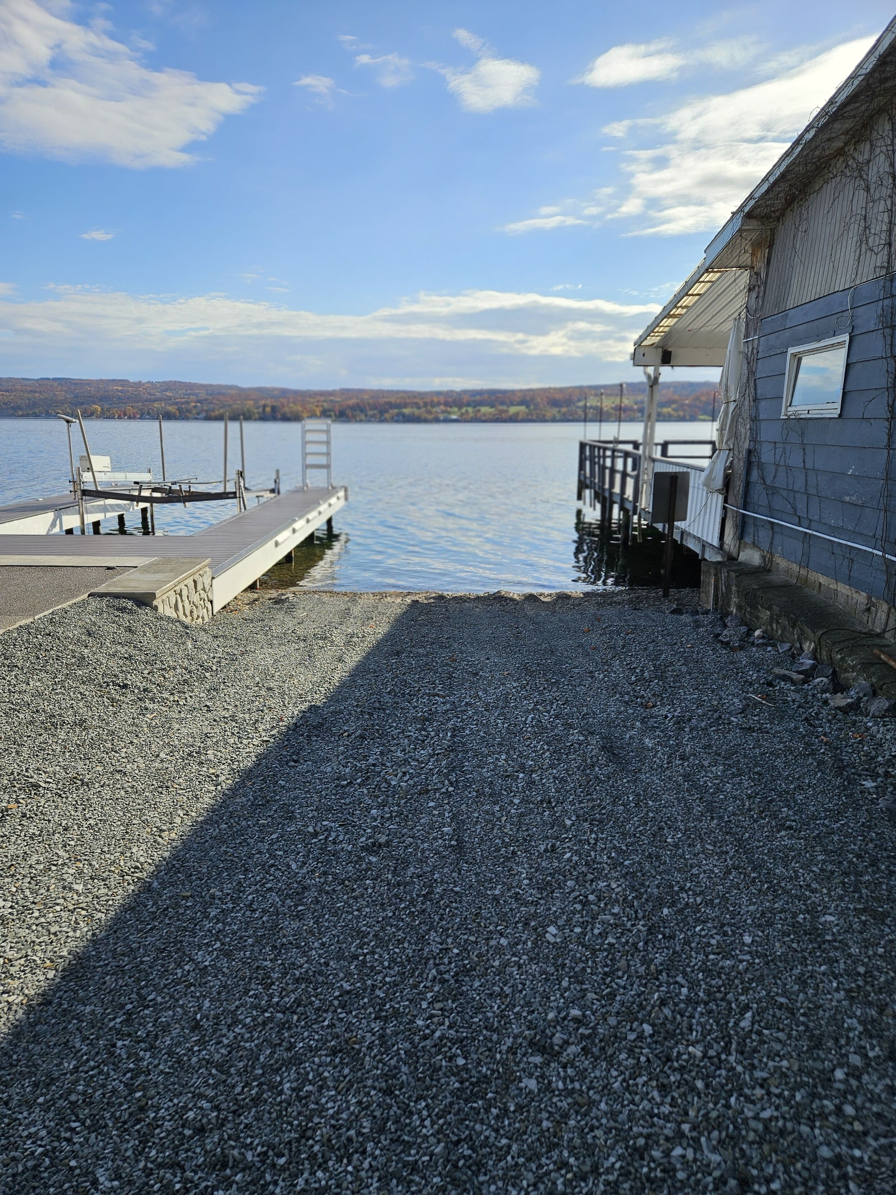 Un muelle se adentra en un lago tranquilo, con un edificio a la derecha.