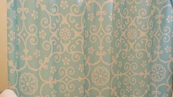 A bathroom with a shower curtain featuring a floral pattern, a white toilet, and a towel rack with a white towel.