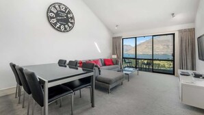 Un salon moderne comprenant un coin repas, un canapé et une grande fenêtre donnant sur les montagnes.