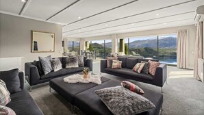 Ein modernes Wohnzimmer mit zwei Sofas, einem Couchtisch und einem großen Fenster mit Blick auf die Berge.