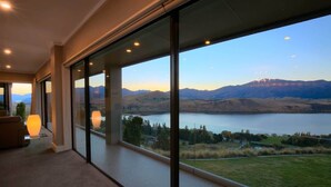 Ein modernes Zimmer mit großen Fenstern und Blick auf einen See und Berge.