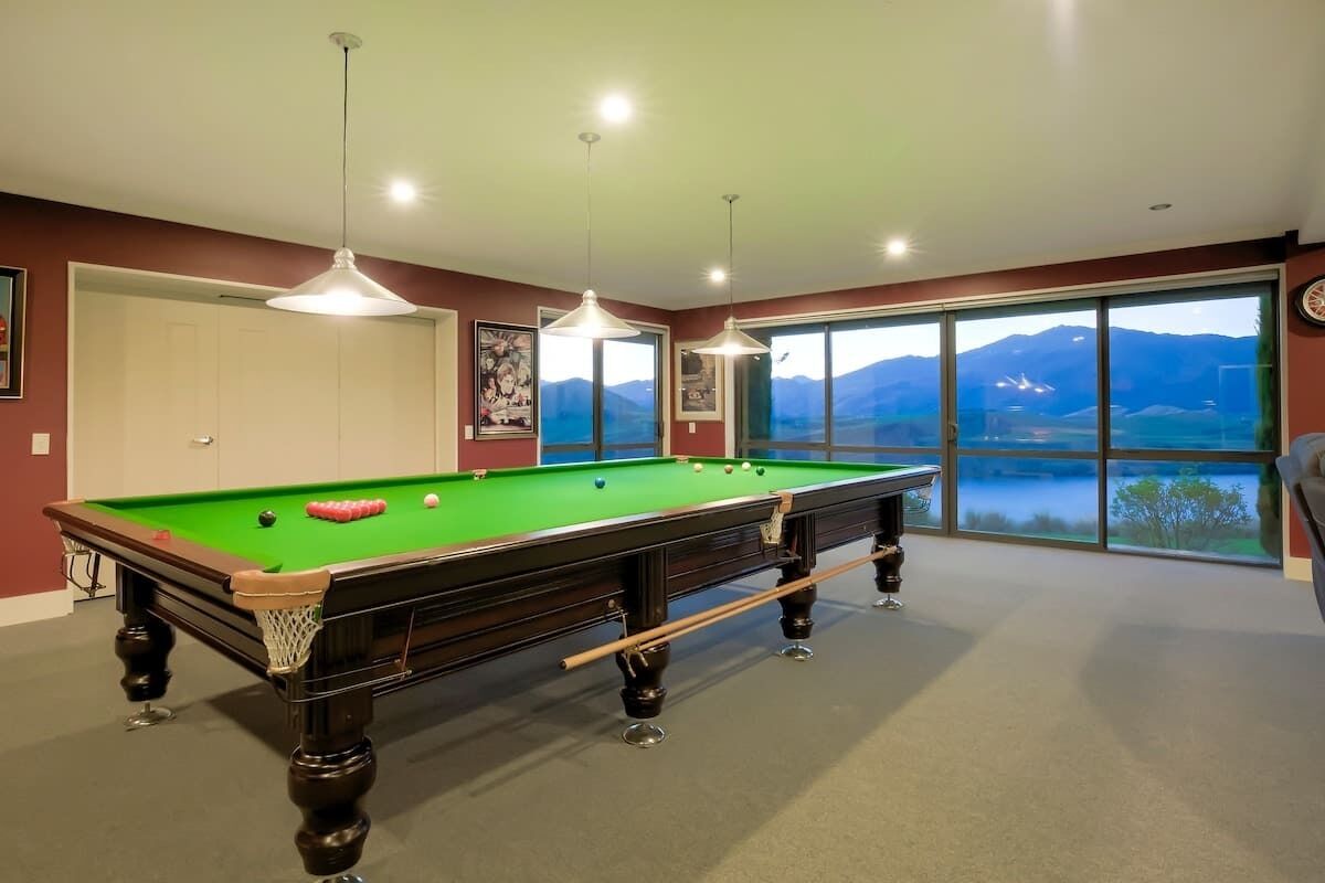 A pool table in a room with large windows offering a mountain view.