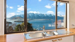 A kitchen with a large window offering a view of a lake and mountains.
