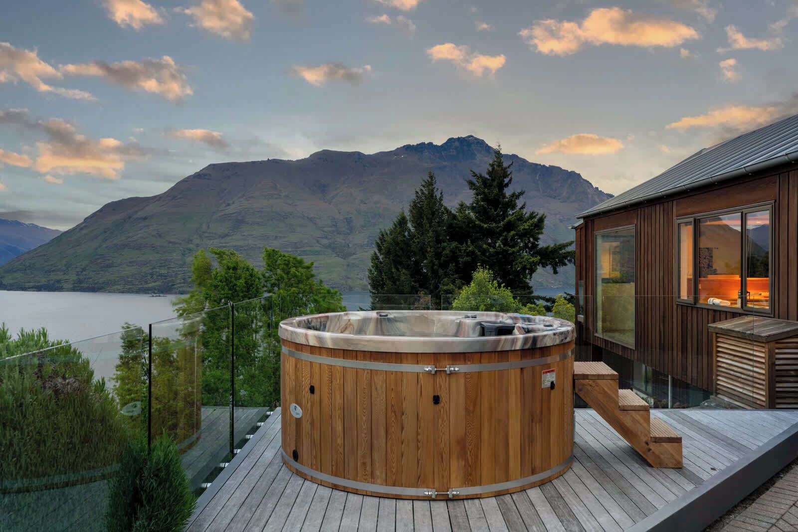 Una vasca idromassaggio in legno su un pontile con vista sulle montagne.