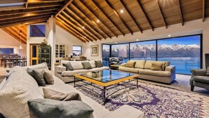 A spacious living room with a high ceiling, large windows offering a mountain view, and a cozy seating area with a coffee table.