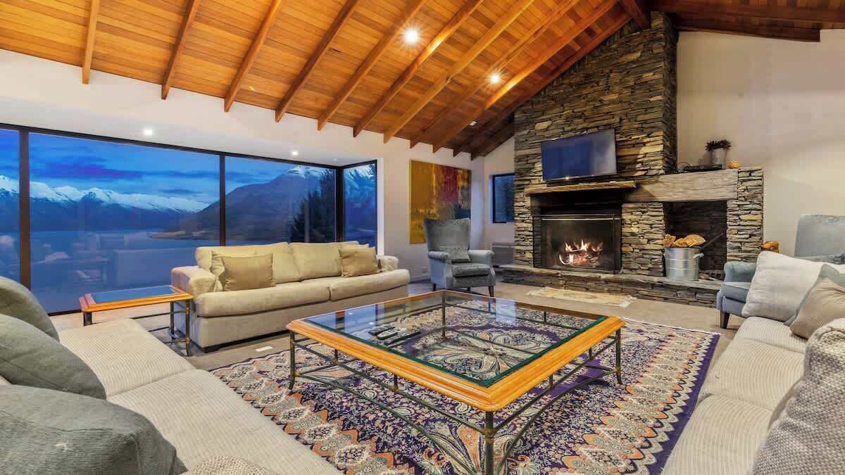 A cozy living room with a stone fireplace, a large window offering a mountain view, and a comfortable seating area.