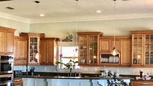 A kitchen with wooden cabinets, a central island, stainless steel appliances, and a hanging light fixture. - A Santa Rosa Sound Waterfront home on 2 acres with a private beach and 200’ dock (Mary Esther)