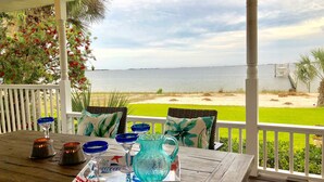 A wooden table with blue glassware and a tray, set on a porch with a view of the beach and ocean. - A Santa Rosa Sound Waterfront home on 2 acres with a private beach and 200’ dock (Mary Esther)