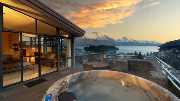 Ein modernes Hotelzimmer mit einer Glaswand und Blick auf eine gebirgige Landschaft sowie einer Whirlwanne.