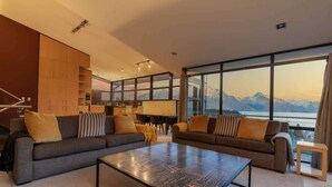 Ein modernes Wohnzimmer mit zwei Sofas, einem Couchtisch und großen Fenstern mit Blick auf die Berge.