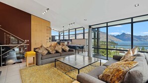 Ein modernes Wohnzimmer mit einer Couch, einem Couchtisch und Blick auf Berge und einen See.