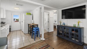A modern kitchen with white cabinets, a blue stool, and a dining table.