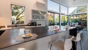 Una cocina moderna con una isla grande, sillas blancas y vistas al exterior.