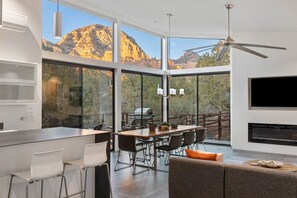 A modern kitchen with a large island, dining area with chairs, and a TV mounted on the wall. - Zen House, Views From All Rooms, Hot Tub, Fire Pit, Bocce Ball Court (Sedona)