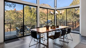 Amplia habitación con un gran comedor, sillas cómodas y vistas a un paisaje montañoso a través de amplias ventanas.
