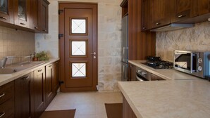 A compact kitchen with wooden cabinets, a built-in oven, and a gas stove. - Faethon, eco stone villa with private pool and sea view (Rethymno)