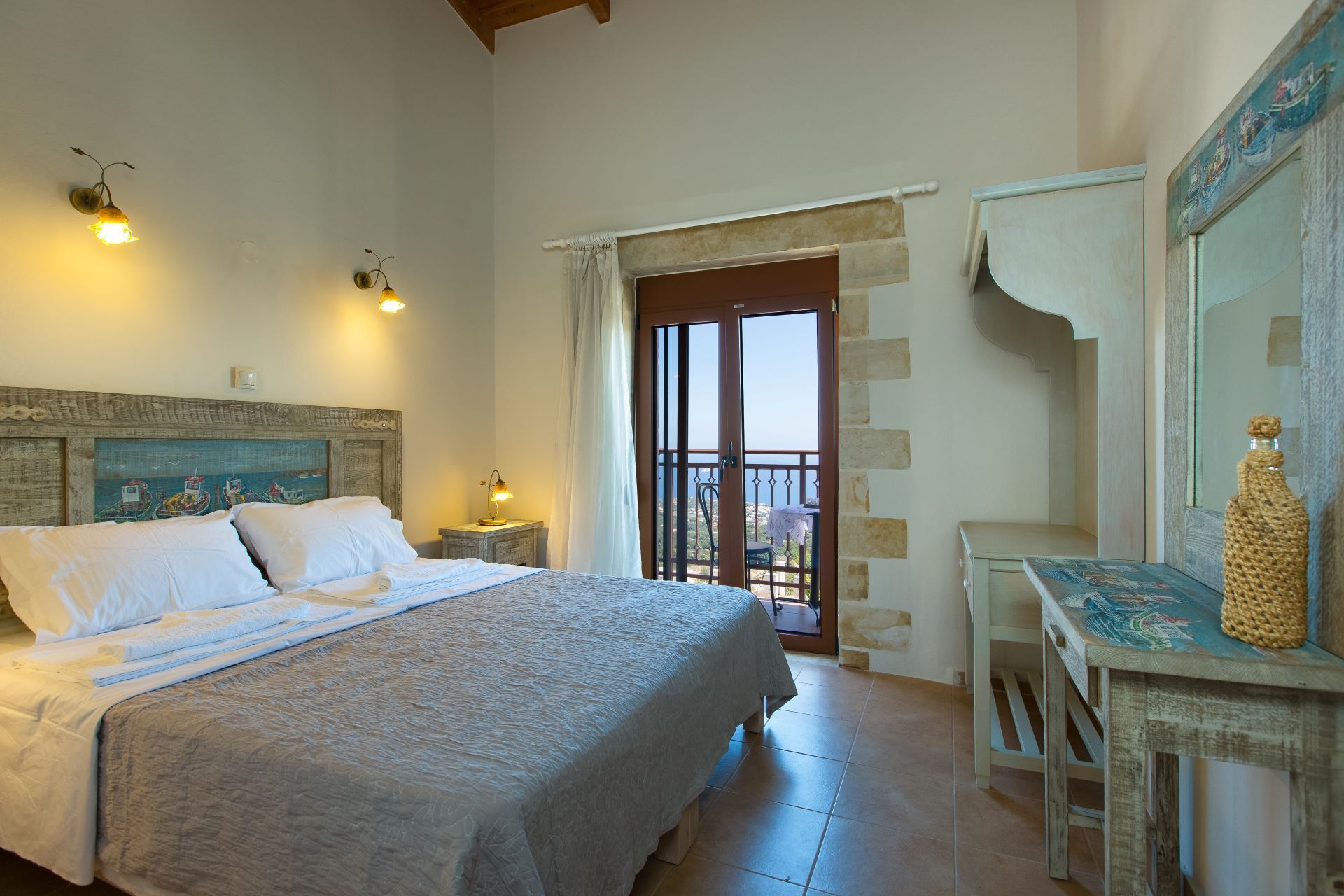 A bedroom with a bed, bedside lamps, a balcony door, and a table with a bottle.