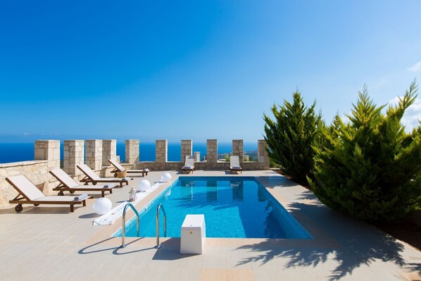 Un espace piscine avec des chaises longues et vue sur la mer.