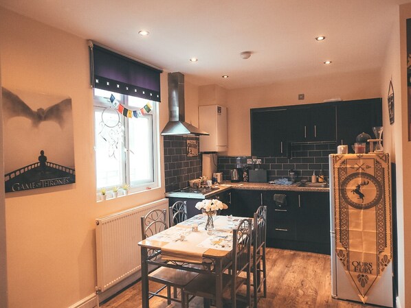 A compact kitchen with a dining area, featuring a window with a view, a stove, and a refrigerator.