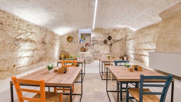 A rustic dining area with stone walls, wooden tables, and chairs. - Casa Magadè (Manduria)