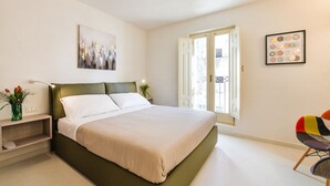 A modern bedroom with a large bed, a bedside table with a lamp, and a chair. - Casa Magadè (Manduria)