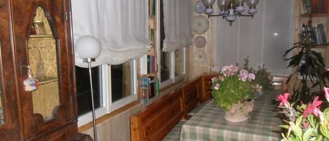 A dining area with a wooden table, chairs, a chandelier, and a window with curtains.