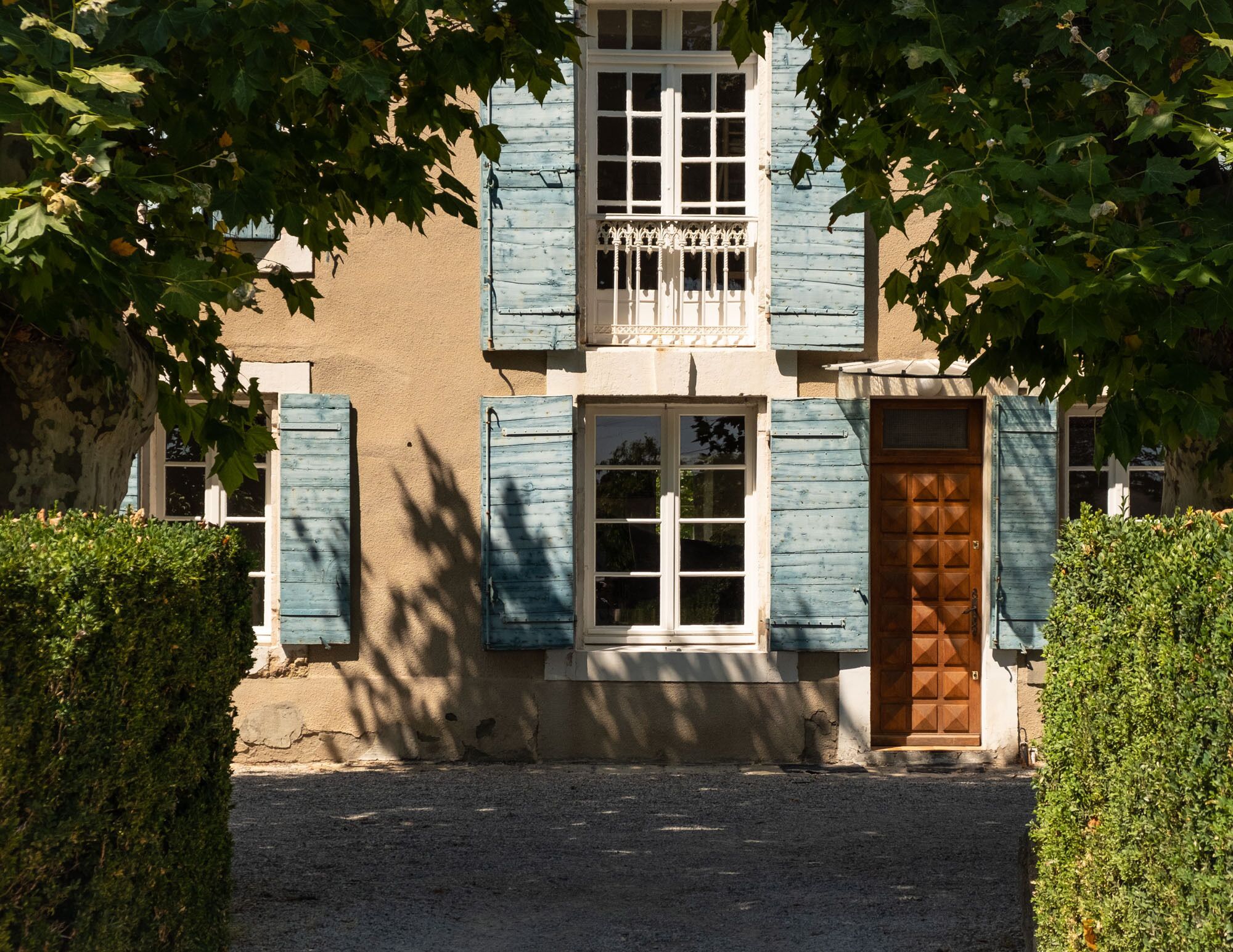 A building with a traditional facade, featuring a central window with shutters, a wooden door, and a small balcony with a railing.