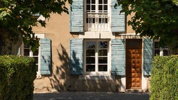 A building with a traditional facade, featuring a central window with shutters, a wooden door, and a small balcony with a railing.