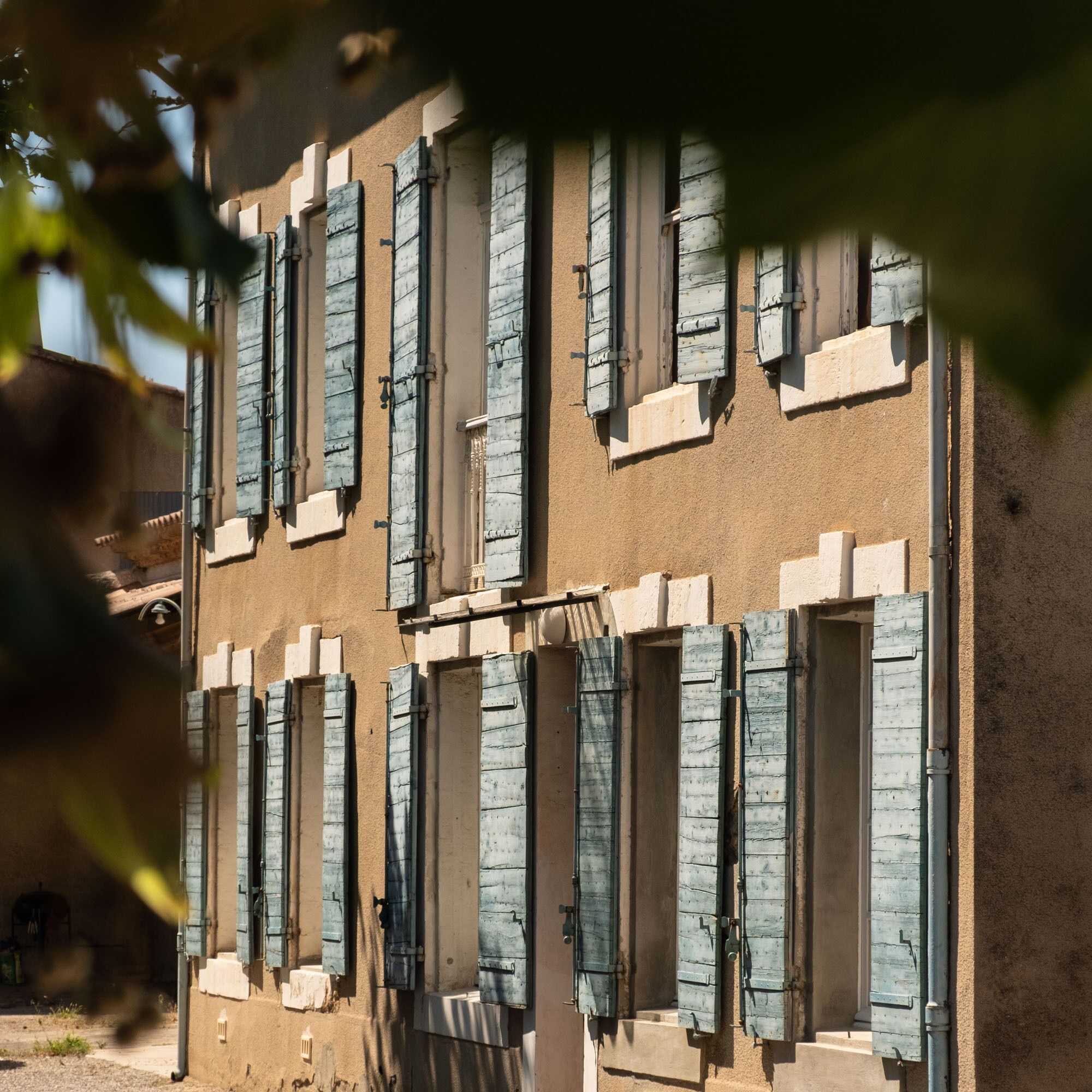A building with multiple windows, some with shutters, and a textured wall.
