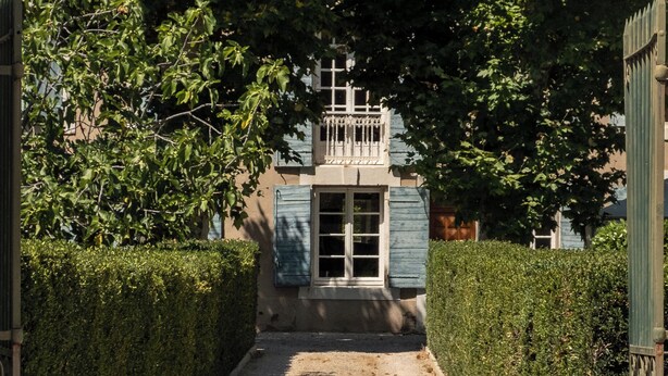 A narrow, gravel pathway leading to a building with a traditional facade, surrounded by dense hedges. - Pélissanne in Provence (Pélissanne)