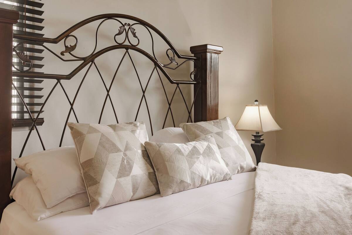 A neatly made bed with patterned pillows and a bedside lamp.