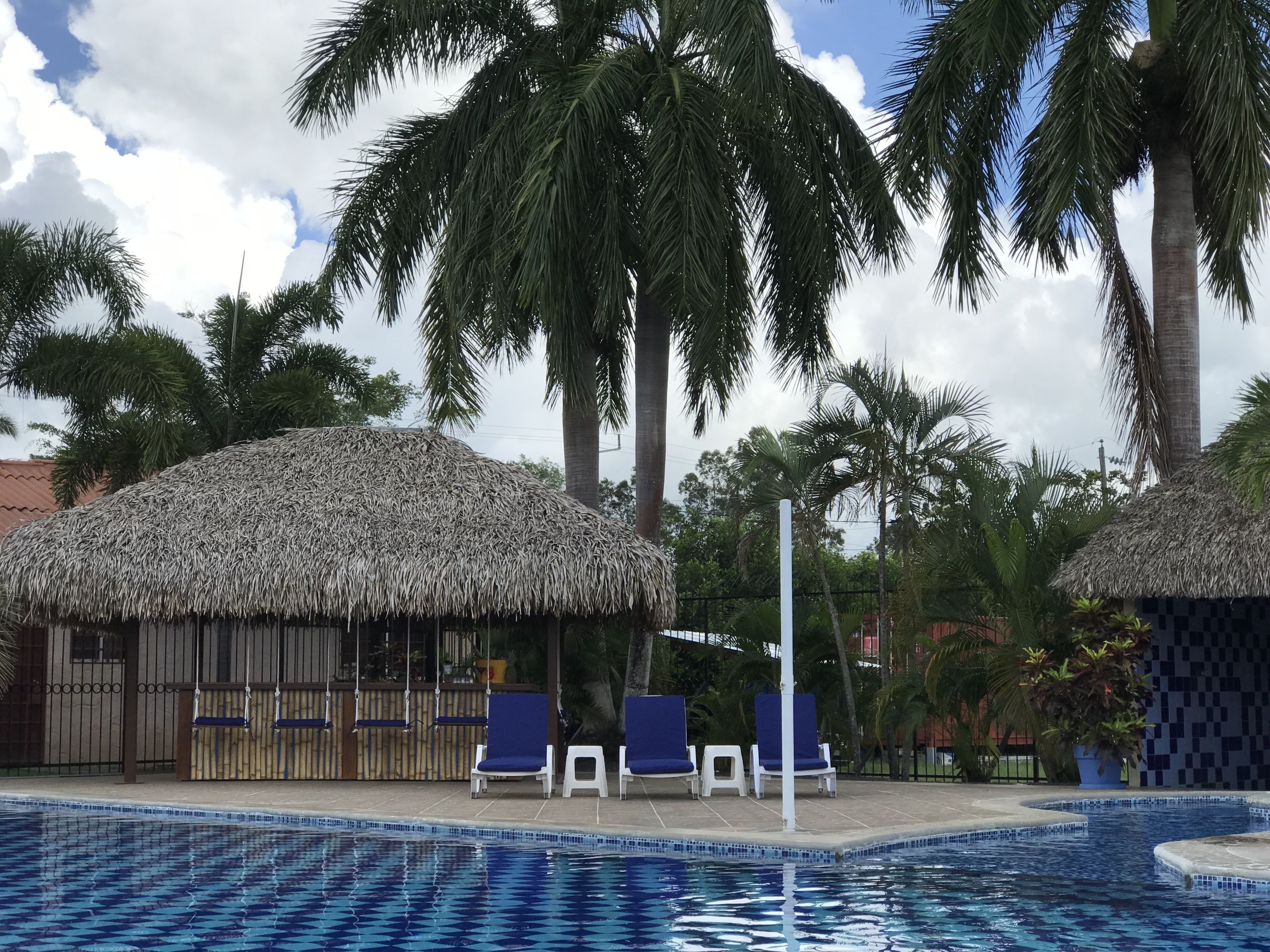 Un área de piscina con sillones de descanso y cabañas de techo de paja.
