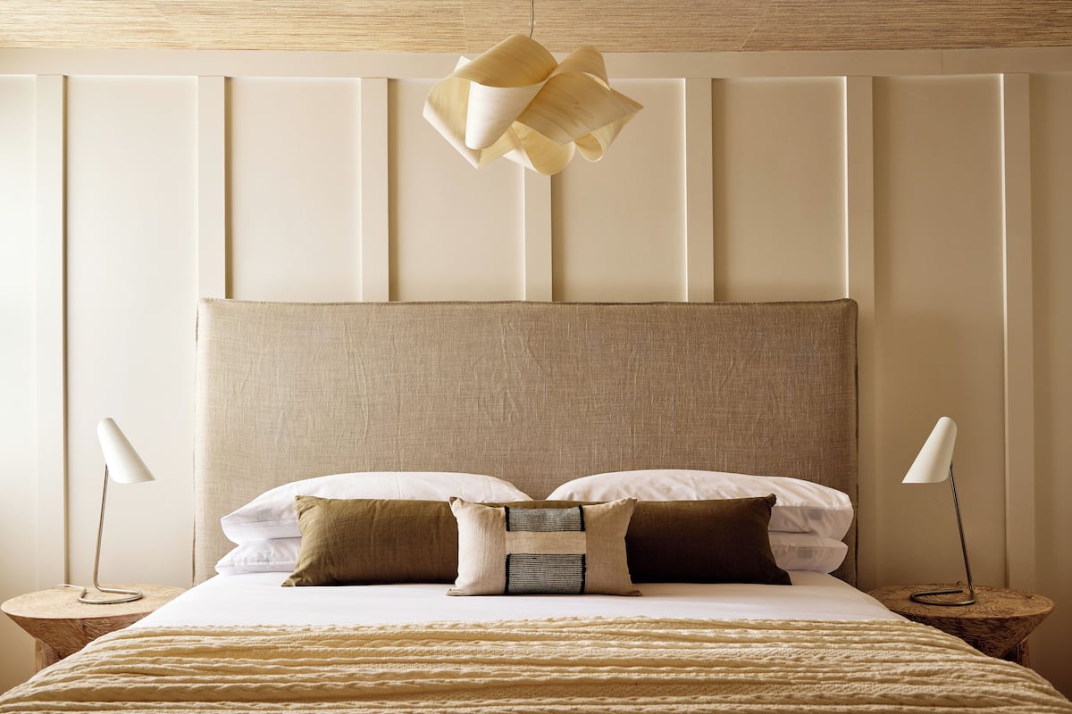Un dormitorio ordenado con una cama grande, dos mesitas de noche y una lámpara colgante.