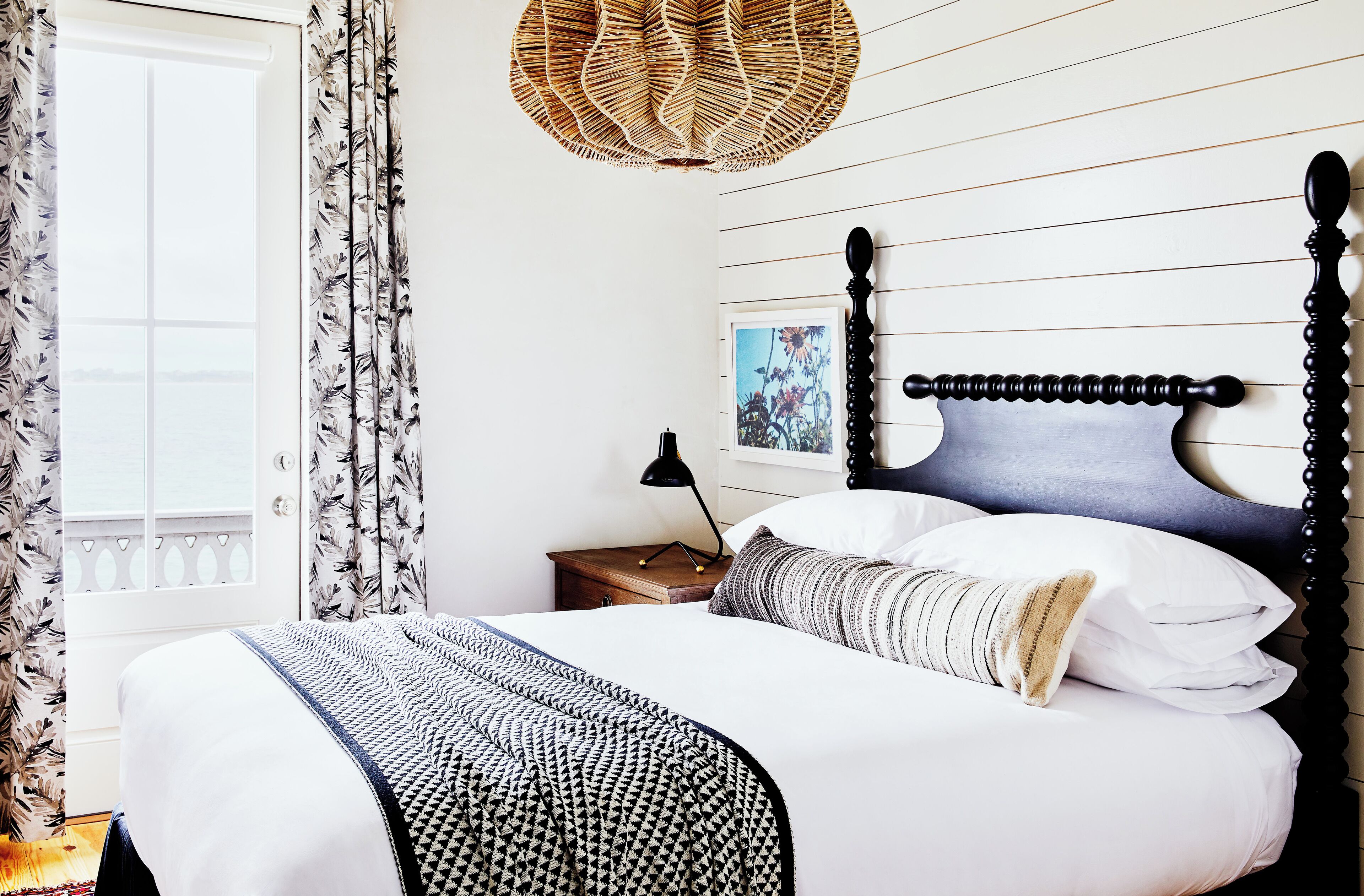 A neatly made bed with a patterned blanket, a bedside lamp, and a framed picture on the wall.