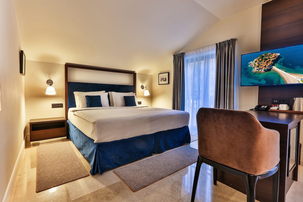 Une chambre d’hôtel équipée d’un lit, d’un bureau, d’une chaise, d’une télévision et offrant une vue sur la côte.