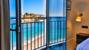 Ein Zimmer mit einer großen Schiebeglasdoor, die auf einen Balkon mit Blick auf das Meer und Gebäude führt.