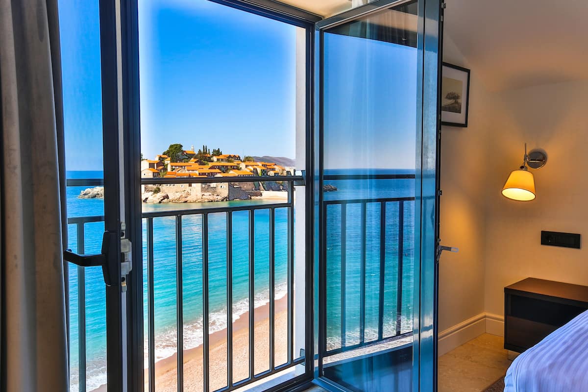 Une pièce dotée d’une grande porte-fenêtre coulissante donnant sur un balcon avec vue sur la mer et les bâtiments.