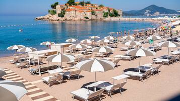 En la playa, sillas reclinables de playa, sombrillas, toallas de playa