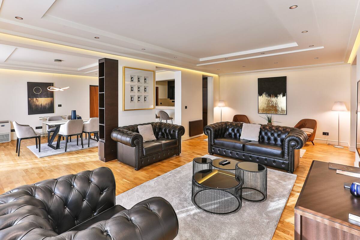 Un salon moderne avec des canapés en cuir, un coin repas et un grand tableau accroché au mur.