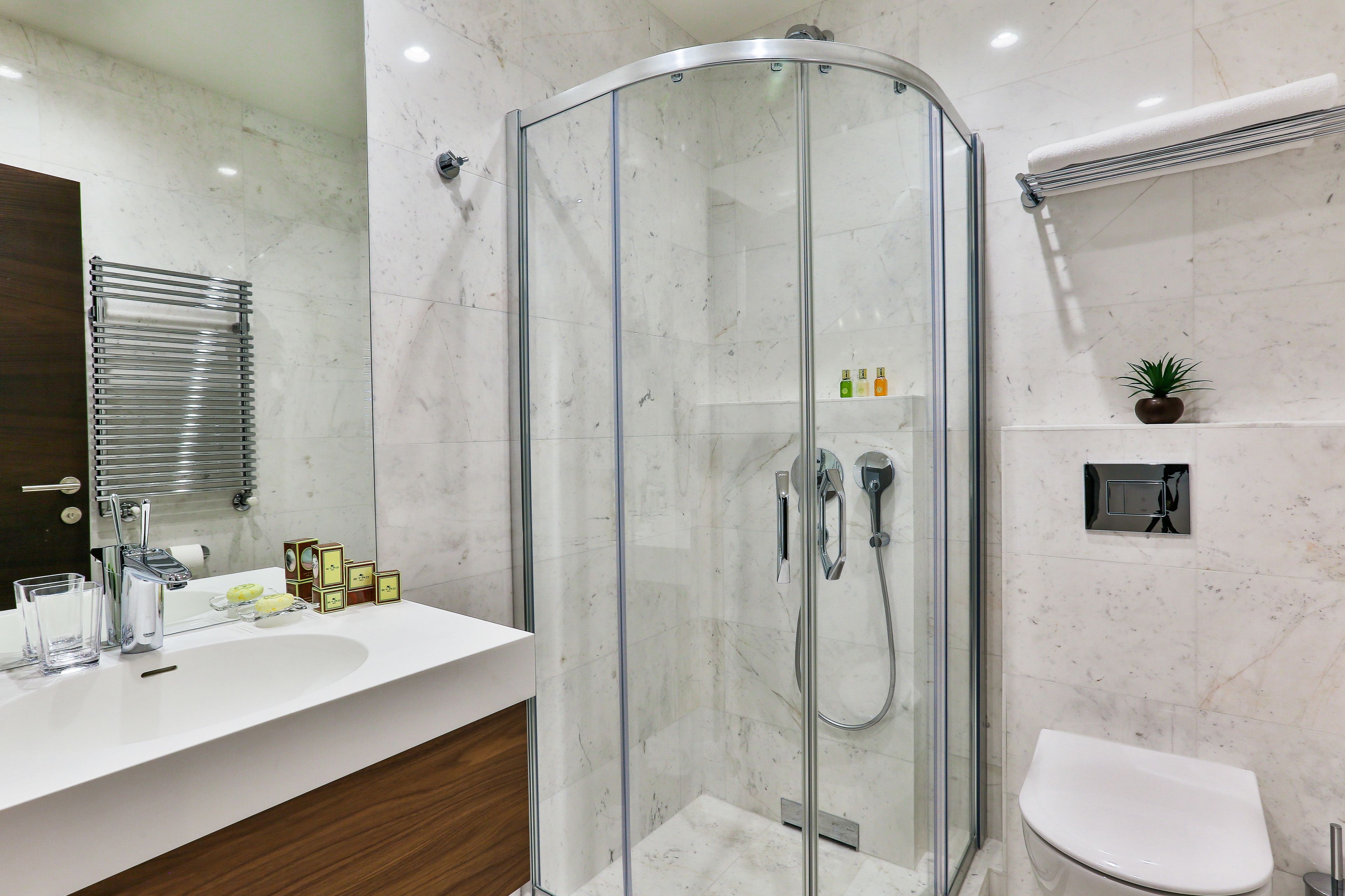 A modern bathroom with a glass-enclosed shower, a white sink, and a toilet.