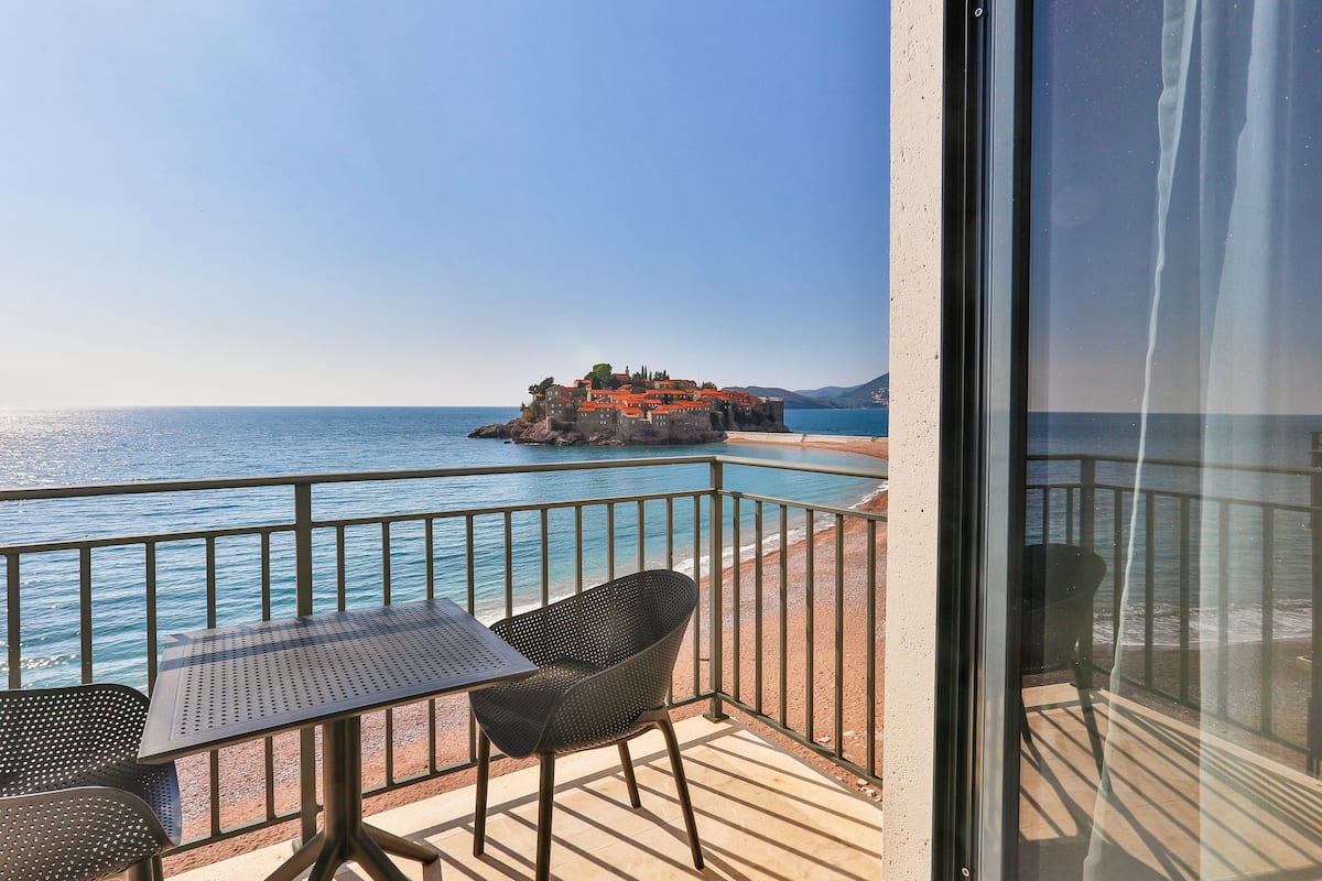 Un balcon avec une table et des chaises, offrant une vue sur la côte et un bâtiment historique.