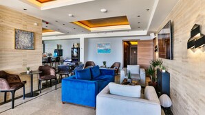 Ein modernes Interieur mit einem blauen Sofa, weißen Sessel und einem Essbereich.