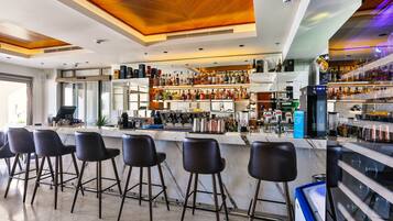 Zona bar moderna con un bancone in marmo, sgabelli da bar neri e una selezione di bottiglie di liquore.