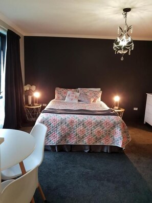 Une chambre à coucher avec un lit, des tables de chevet, un lustre et une chaise.