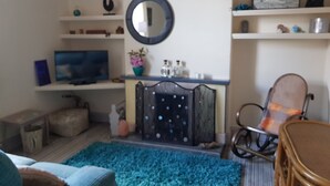 A living room with a TV, a round mirror, a chair, and a sofa. - Lingdale 4 Bedroom House & Trundlebed Option (Saltburn-by-the-Sea)