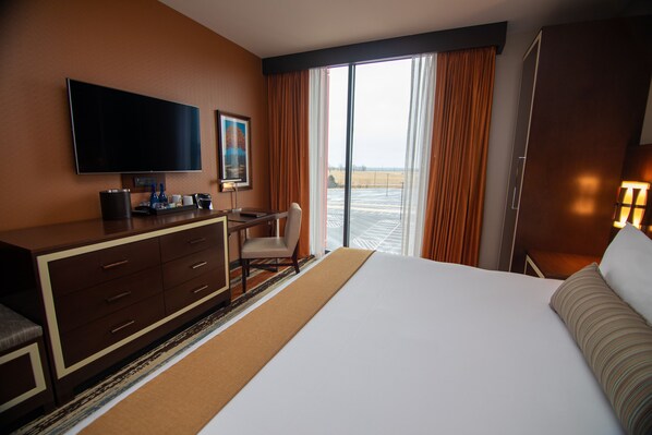 Habitación de hotel con una cama grande, un escritorio, un televisor y vistas al exterior.