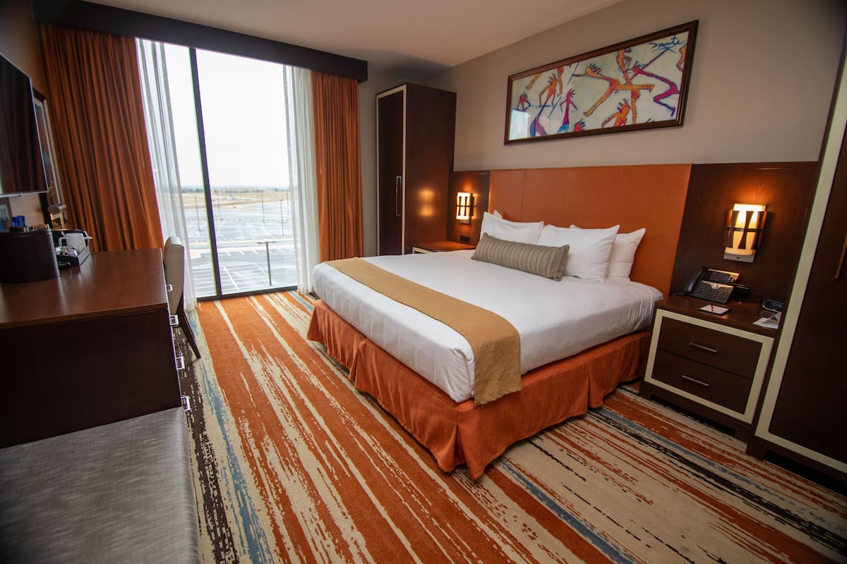 Een hotelkamer met een groot bed, een bureau, een stoel, een nachtkastje met een telefoon en een schilderij aan de muur.