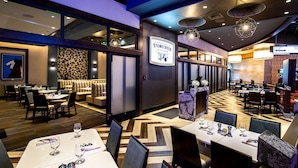 Un restaurante con varias zonas de comedor, un letrero que dice Stonecreek Kitchen y diferentes opciones de asientos.